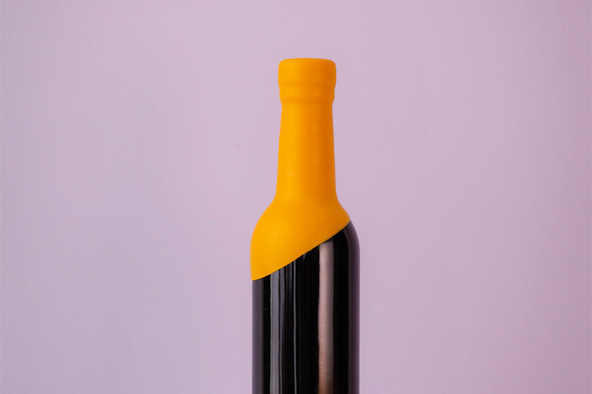Black bottle with yellow sealing wax in all the neck of the bottle leaving it in diagonal shape, and the background is in lilac color