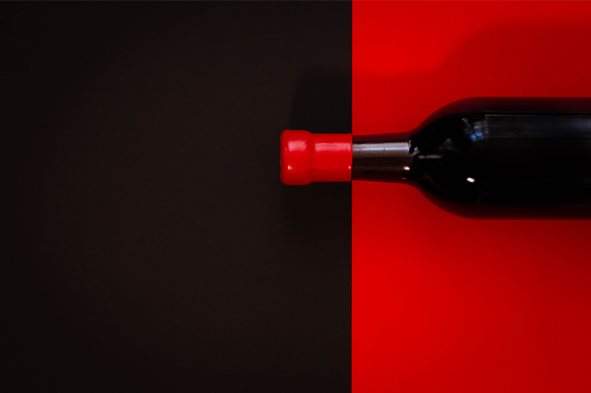 black bottle with red background, and red sealing wax on the neck of the bottle with black background