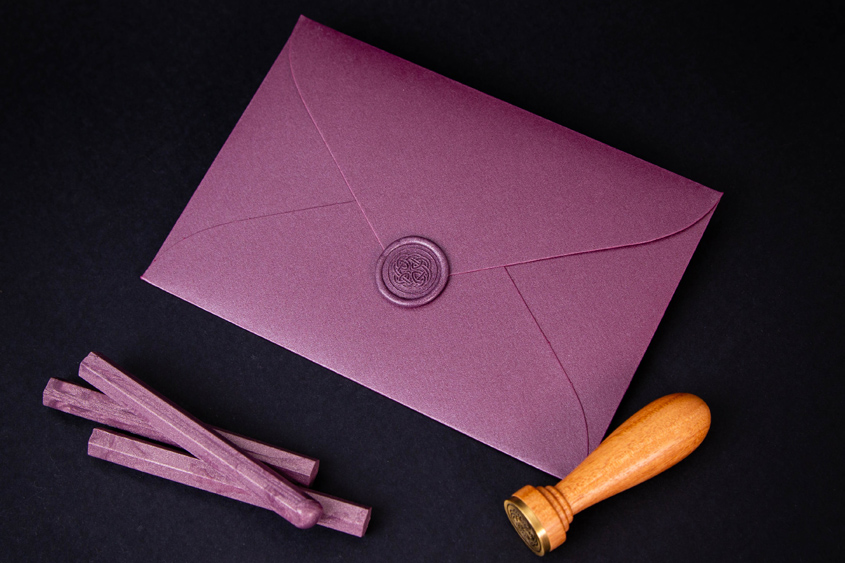 purple envelope with violet sealing wax sticker in celtic knot design, and violet sealing wax sticks