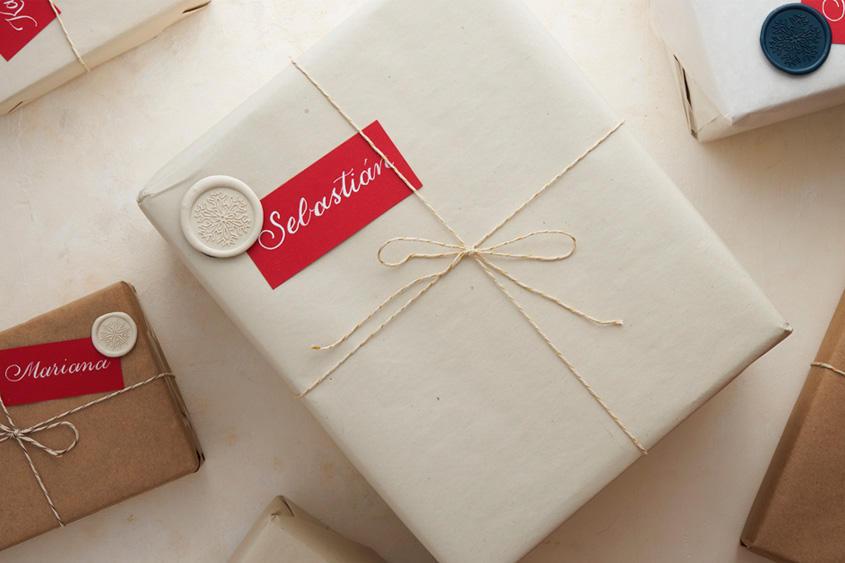 Gift box with a red card that has the name Sebastian written in calligraphy, and an ivory sealing wax medallion with a snowflake design