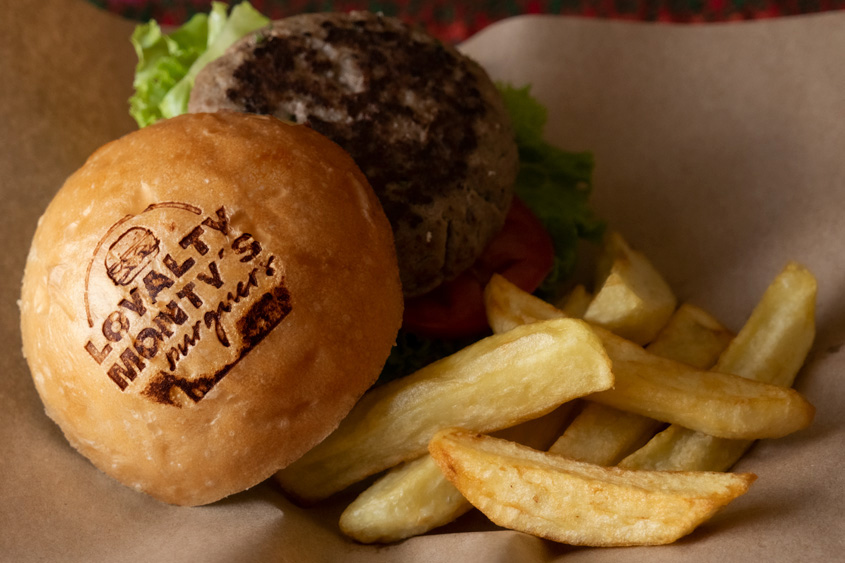 Hamburger with French fries, with Loyalty Monty's burgers restaurant logo stamped with a heat stamp.