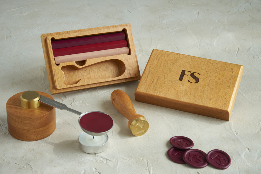 Wooden case from a sealing wax set that has engraved FS initials. sealing wax bars in red violet, red and pink, mini melting base and medallions 