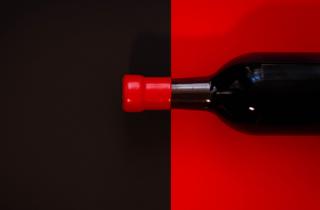 black bottle with red background, and red sealing wax on the neck of the bottle with black background