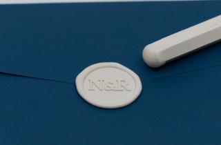 Sealed blue envelope with initials N&R design in ivory color, with a sealing wax bar for paper that was slightly melted at the tip