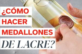 The image shows a close-up of a bottle of white wine. One hand is holding the bottle near the neck, and another is applying a tan wax seal to the glas