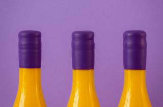 three yellow bottles in Lilac background, and purple sealing wax on the neck of the bottles